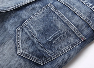 Detail of blue denim shorts back pocket with double stitching and washed texture