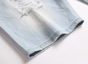 Détail macro de l'ourlet en denim bleu clair avec trous déchirés et bords effilochés