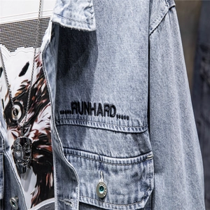 Close-up of light blue denim jacket featuring black RUNHARD embroidery and chest pocket