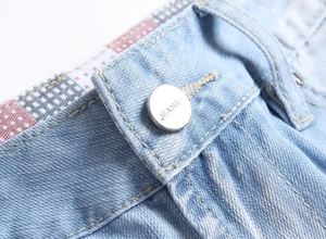 Makro-Detail der Denim-Shorts-Taille mit silbernem Metallknopf und Kontrastnähten