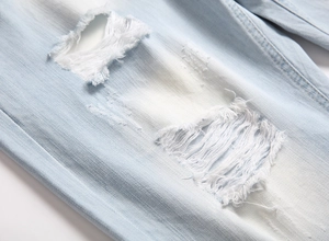 Détails de près du short en jean bleu clair délavé avec finitions déchirées et fils blancs