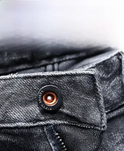 Detailed close-up of the black denim jeans waist featuring a branded metallic button closure