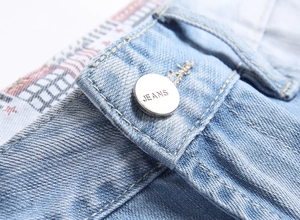 Detail of light blue denim jeans waist with a polished silver button and engraved jeans text