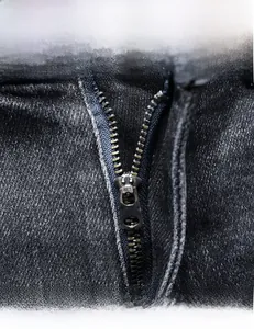 Close-up of high-quality metal zipper detail on men's slim fit black denim jacket