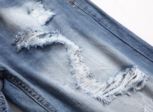 Detailed macro view of distressed light blue denim shorts with heavy fraying and ripped effect