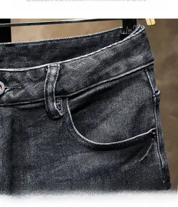 Detail view of black denim jeans waistband featuring metal button and washed texture