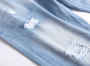 Detail showing the light blue denim fabric texture and ripped distressed hole design
