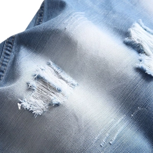 Gros plan sur un jean bleu clair avec des détails déchirés et des textures effilochées