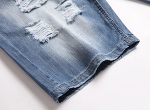 Detail of blue washed denim shorts featuring distressed ripped texture and sewing craft