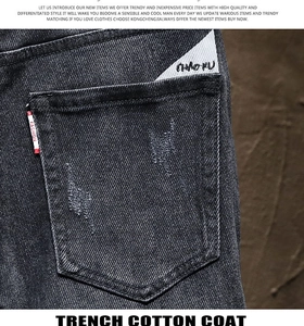 Detail of slim black jeans featuring a back pocket with a red label and logo patches