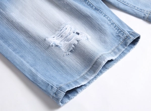 Detail of light blue denim shorts featuring distressed rips and fringed hem edges