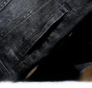 Detailed close-up showing reinforced pocket stitching on black denim jacket