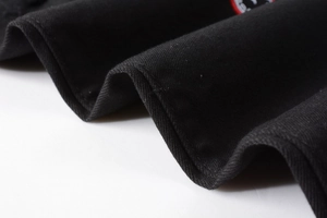 Gros plan sur la texture du denim noir avec écusson brodé et détails d'aspect vieilli