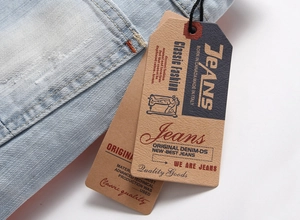 Dettaglio di denim azzurro con trama saia e cartellini del marchio su uno sfondo chiaro