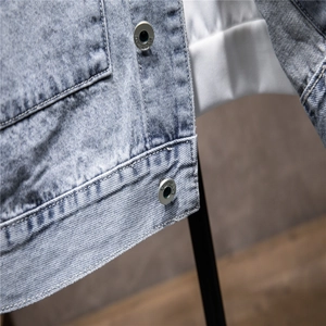 Detail shot of light blue denim fabric texture and silver metal buttons on a casual jacket