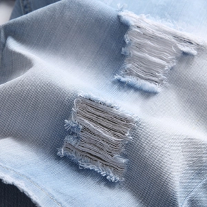 Nahaufnahme der hellblauen Denim-Shorts mit Distressed-Löchern und weißen Fransenfasern