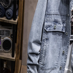 Detail of light blue denim jacket texture with chest pocket and metallic buttons