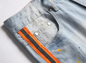 Dettaglio vita in denim azzurro con fettuccia arancione e schizzi di vernice colorata