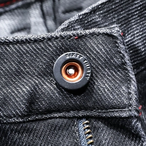 Detail of metal button on black slim fit jeans with Sixty Thirty engraving