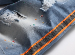 Detail of distressed light blue denim with paint splatters and side stripe webbing