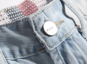 Dettaglio della vita di jeans azzurri con bottone argentato e cuciture accurate