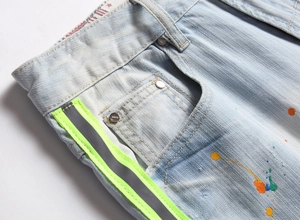 Détail du short en jean bleu clair avec bandes réfléchissantes néon et éclaboussures de peinture
