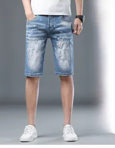 Close-up of light blue denim shorts with distressed holes and colorful paint splatter details