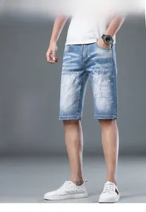 Detail view of light blue denim shorts featuring artistic paint splatters and distressed holes