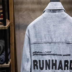 Detail view of denim jacket back showing RUNHARD printed text on washed blue cotton fabric