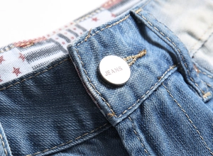 Detail of blue denim shorts showing a metal jeans button and premium red star fabric lining