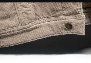 Detailed close-up of corduroy jacket hem featuring a vintage bronze button and ribbed texture