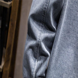 Close-up of blue denim jacket sleeve showing twill texture and reinforced stitching