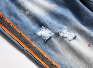 Detailed macro view of light blue denim shorts with paint splatters and side tape