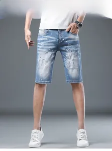 Detail of light blue distressed denim shorts featuring white and orange paint splatter