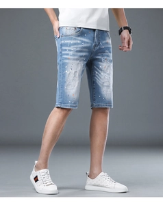 Detail shot of men's denim shorts with distressed holes and colorful paint splatter accents