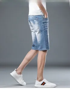 Detail of blue denim shorts featuring artistic orange and white paint splatter design