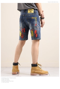 Detail of artistic red and yellow paint splatter on back of blue denim shorts
