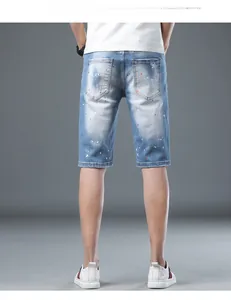 Detail of light blue denim shorts featuring artistic paint splatter and frayed distressed hems