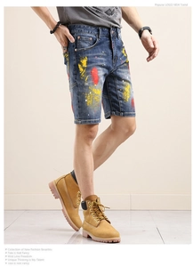 Detail shot of blue denim shorts featuring artistic yellow and red paint splash patterns