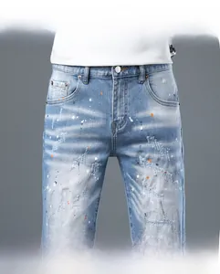 Detailed view of light blue denim shorts with distressed rips and colorful paint splashes