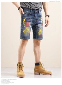 Detail of blue denim shorts featuring artistic yellow and red paint splatter patterns