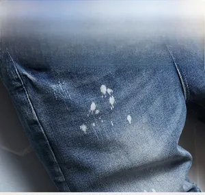 Close-up of blue denim shorts featuring vintage wash and white paint splatter details