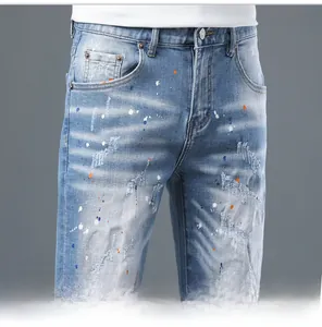 Detailed close-up of distressed denim shorts with paint splatter and metal button detail