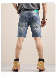 Détail du short en jean bleu avec éclaboussures de peinture et patch en cuir vert au dos