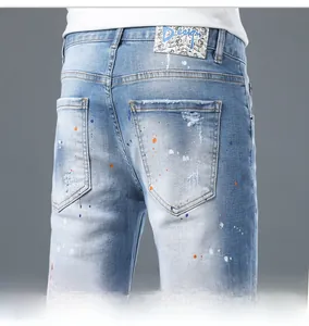 Detail of light blue denim shorts featuring artistic paint splatters and distressed back pocket