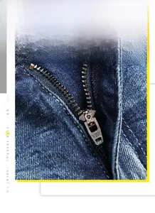 Detailed macro view of the premium YKK metal zipper on washed blue denim jeans