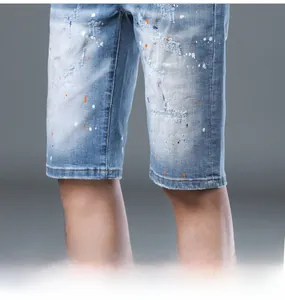 Detail of light blue denim shorts with paint splatters and distressed ripped hem