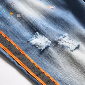 Distressed denim shorts with colorful paint splatters and side webbing stripe