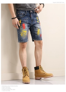 Detail of blue denim shorts with artistic yellow and red paint splatter and red label tag
