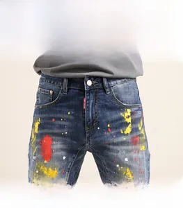 Detail shot of men's blue denim shorts featuring artistic paint splash and red brand tag